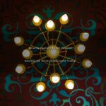 A golden chandelier illuminates against a patterned background.